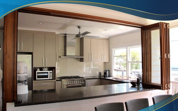 Cửa sổ mở xếp trượt 6 cánh màu vân gỗ được lắp đặt khu vực nhà bếp để làm cửa ngăn giữa khu vực nấu và khu vực bàn ăn để không bị ám mùi nhưng vẫn đảm bảo được sự liên kết giữa 2 khu vực.