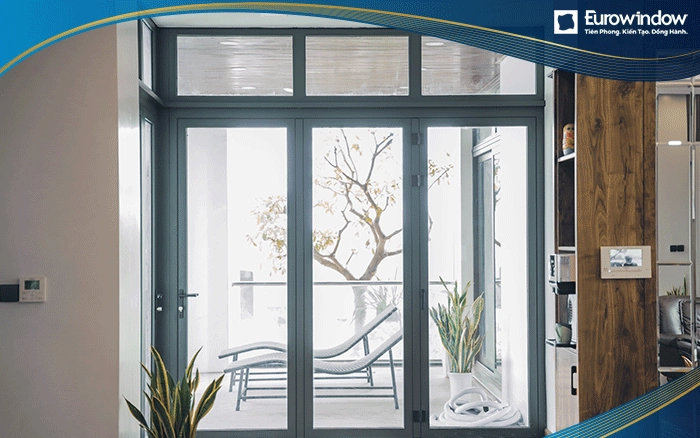 Eurowindow sử dụng cửa nhôm mở quay màu xám 3 cánh kết hợp với vách kính cố định ở trên ở khu vực ban công.