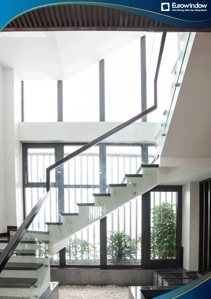 Ở lối đi cầu thang bộ, Eurowindow sử dụng cửa nhôm mở quay, cửa mở hất kết hợp với các vách kính lớn. Cửa và vách kính thay thế mảng tường lớn tạo nên không gian thoáng đãng