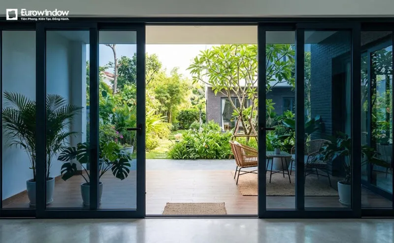 Cửa đi nhôm kính xanh đen 4 cánh mở trượt, tạo lối đi rộng và kết nối không gian trong nhà với sân vườn. (Nguồn: Eurowindow)
