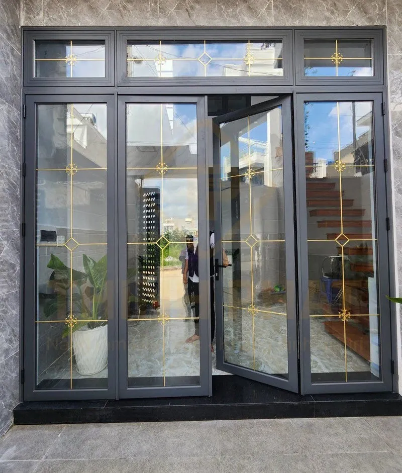 Cửa nhôm kính hộp có nan trang trí lắp ở cửa đi chính ngôi nhà giúp không gian thông thoáng, mở rộng tầm nhìn và thẩm mỹ sang trọng